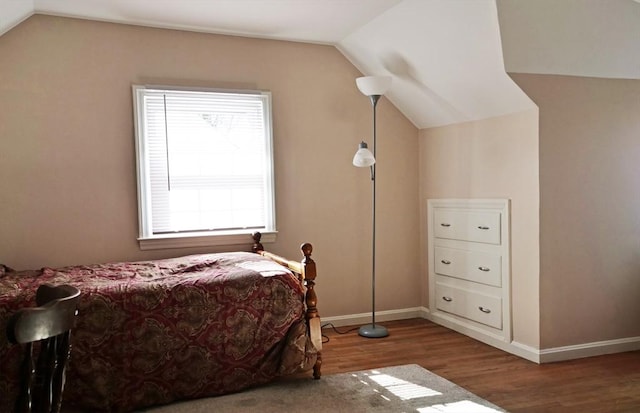 bedroom with baseboards, vaulted ceiling, and wood finished floors