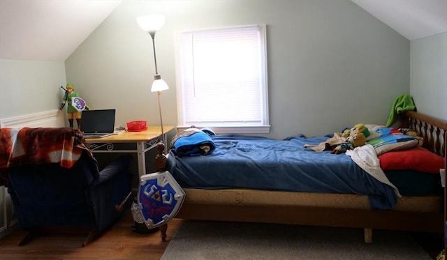 bedroom with wood finished floors and lofted ceiling
