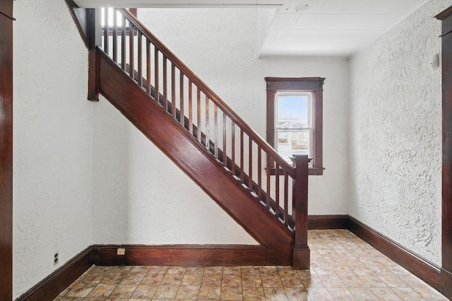 staircase with a textured wall and baseboards