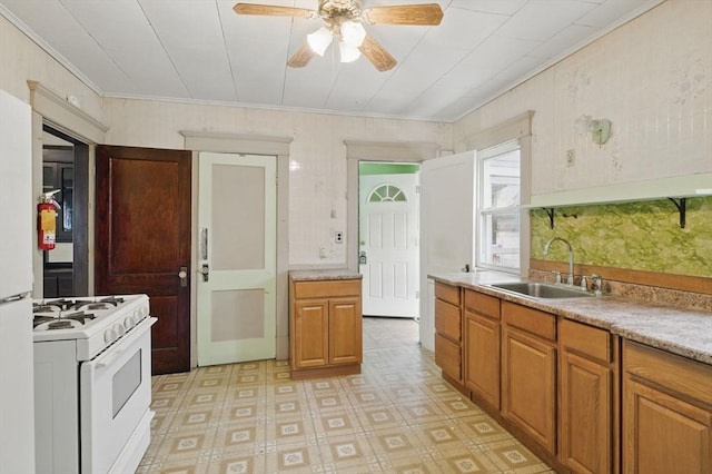 kitchen with light countertops, gas range gas stove, a sink, and brown cabinets