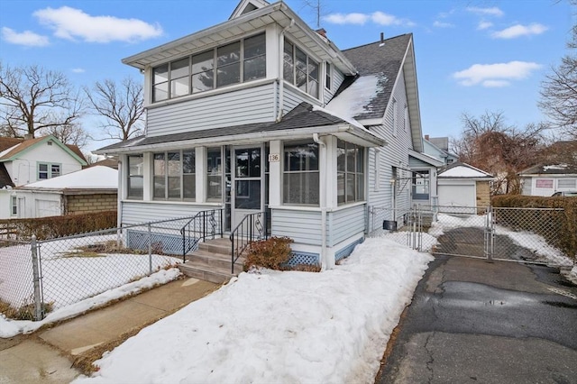 view of front of property with an outbuilding, fence, a sunroom, roof with shingles, and a gate