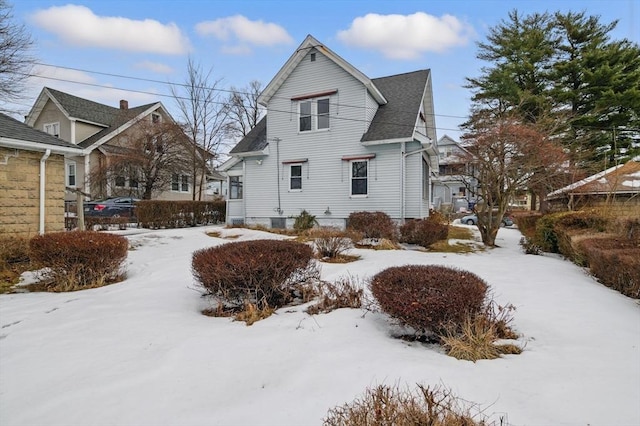 view of snowy exterior with roof with shingles