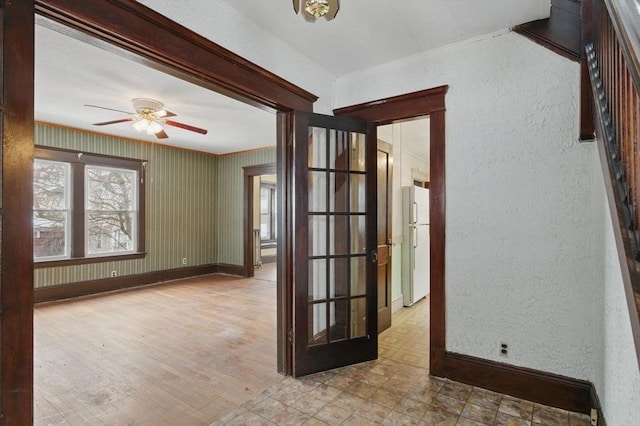 empty room featuring baseboards, a ceiling fan, and a textured wall