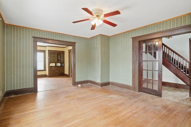 empty room featuring stairs, french doors, wood-type flooring, and wallpapered walls