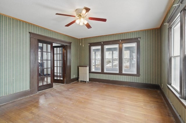 empty room featuring radiator, baseboards, hardwood / wood-style floors, and wallpapered walls