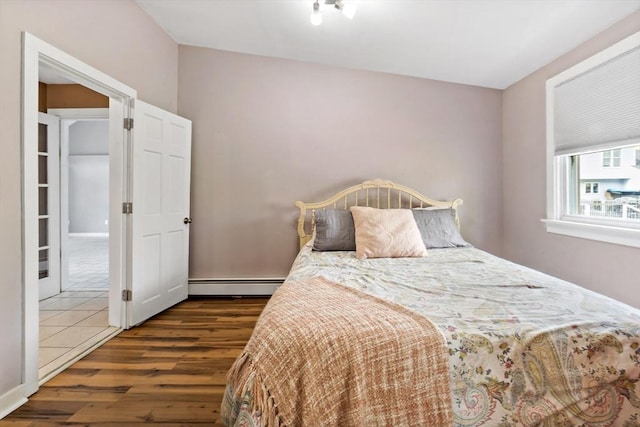 bedroom with wood finished floors and baseboard heating