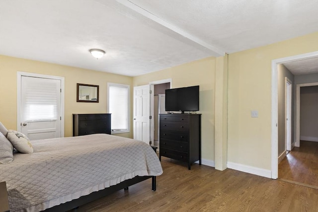 bedroom featuring baseboards, wood finished floors, and multiple windows