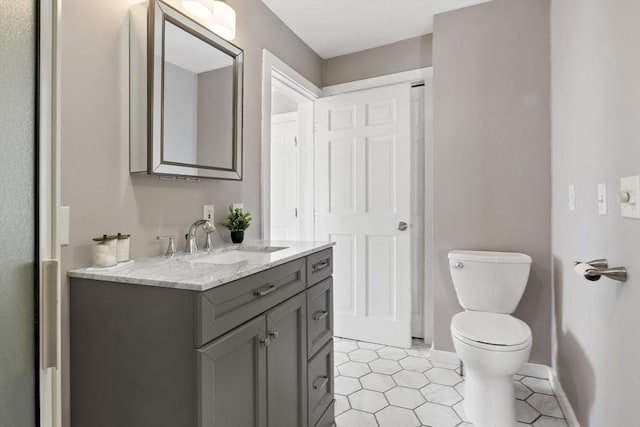 bathroom with toilet, baseboards, tile patterned flooring, and vanity