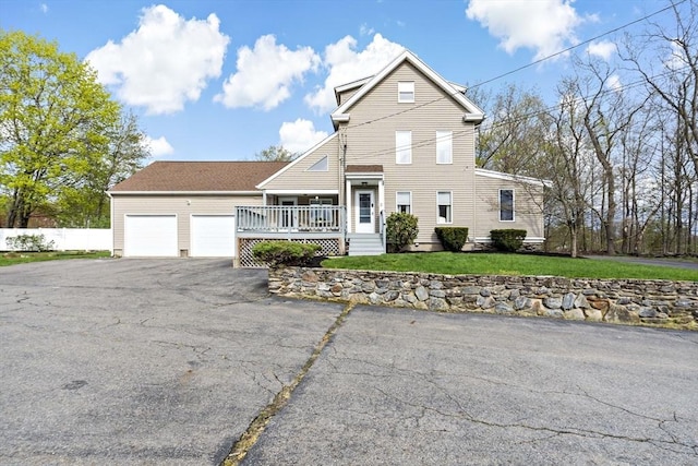 traditional-style house with fence, a garage, a wooden deck, a front yard, and driveway