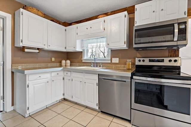 kitchen featuring a sink, white cabinetry, light tile patterned flooring, and stainless steel appliances