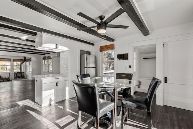 dining room with ceiling fan, beamed ceiling, dark wood finished floors, and a healthy amount of sunlight