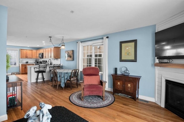 living area featuring visible vents, light wood-style floors, baseboards, recessed lighting, and a large fireplace