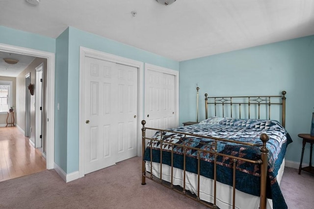 bedroom featuring baseboards, carpet, and two closets