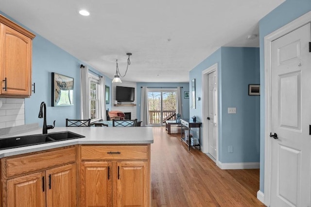 kitchen with a peninsula, wood finished floors, open floor plan, light countertops, and a sink