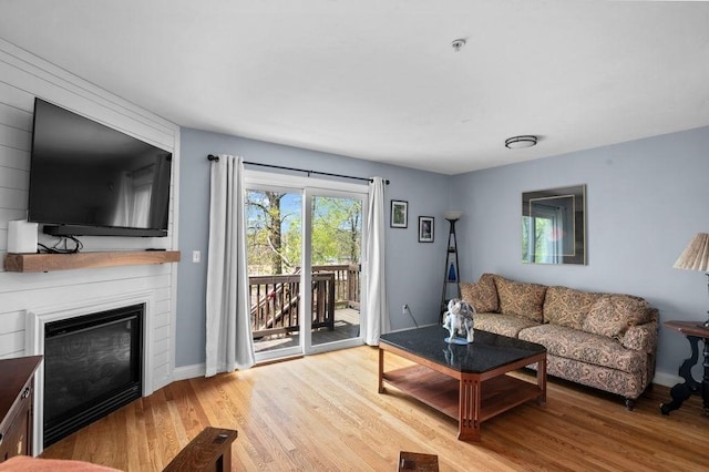 living area with a large fireplace, baseboards, wood finished floors, and visible vents