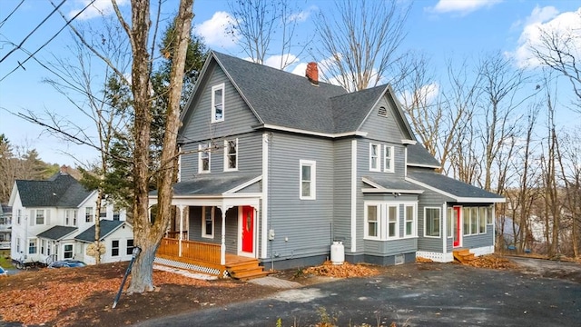 view of front of home with roof with shingles, a porch, and a chimney