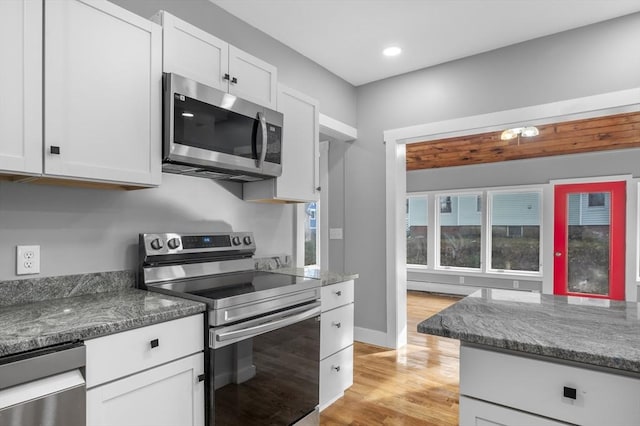 kitchen featuring baseboards, light wood finished floors, recessed lighting, appliances with stainless steel finishes, and white cabinetry