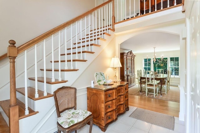 stairway with wood-type flooring and a notable chandelier