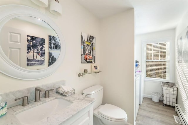 bathroom with hardwood / wood-style flooring, vanity, toilet, and a baseboard heating unit