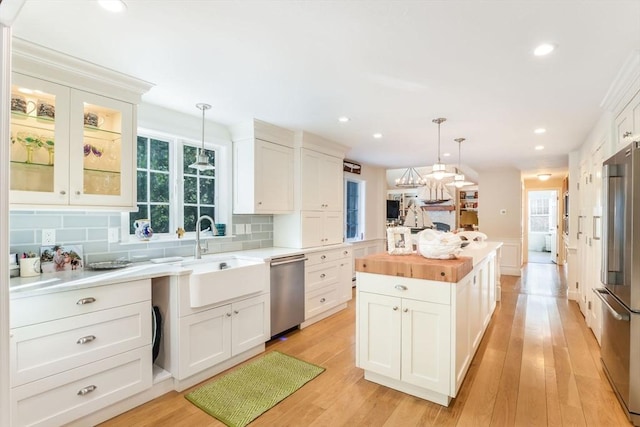 kitchen featuring white cabinets, stainless steel appliances, and decorative light fixtures