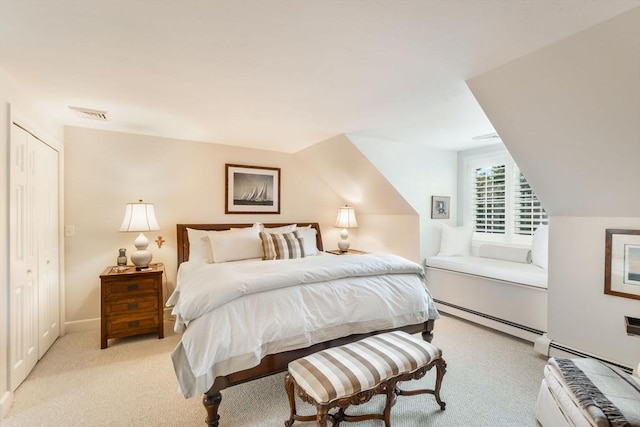 carpeted bedroom with baseboard heating, a closet, and vaulted ceiling