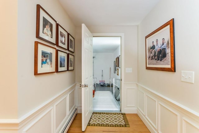 corridor with light hardwood / wood-style floors and a baseboard heating unit