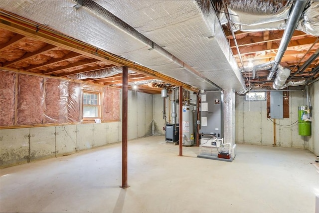 basement featuring electric panel, heating unit, and water heater