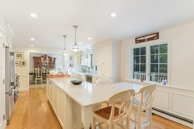 kitchen with pendant lighting, a baseboard heating unit, white cabinets, light hardwood / wood-style floors, and stainless steel appliances