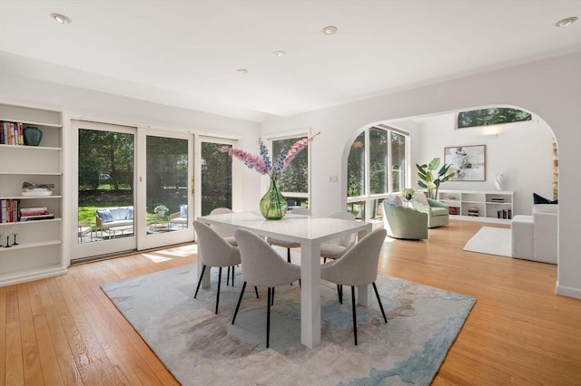 dining space featuring recessed lighting, arched walkways, plenty of natural light, and light wood finished floors