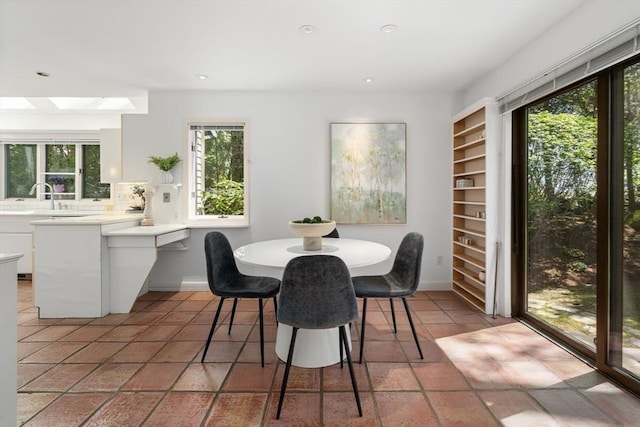 dining room with baseboards, a healthy amount of sunlight, and a skylight