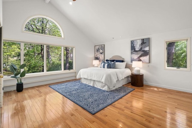 bedroom with baseboards, beamed ceiling, high vaulted ceiling, and hardwood / wood-style flooring