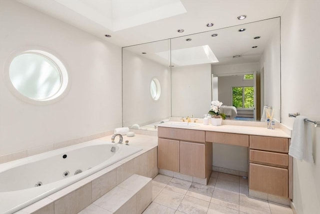 full bathroom with a skylight, vanity, a jetted tub, and recessed lighting