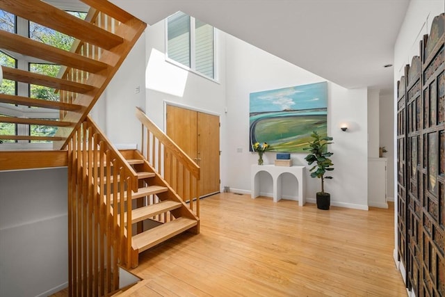 foyer with baseboards, stairs, and wood finished floors