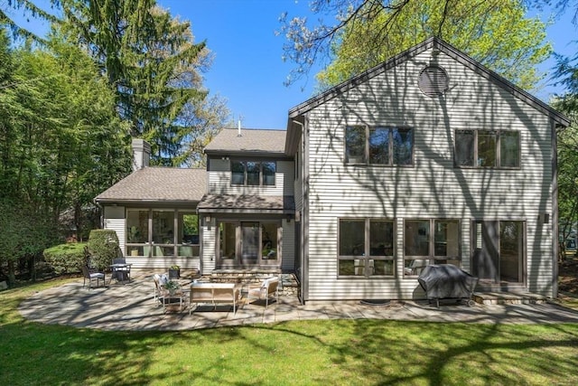 back of property with a yard, a chimney, and a patio area