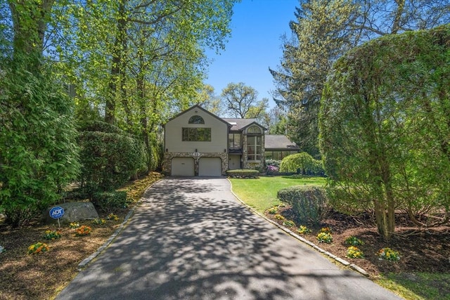split level home with an attached garage, driveway, and a front yard