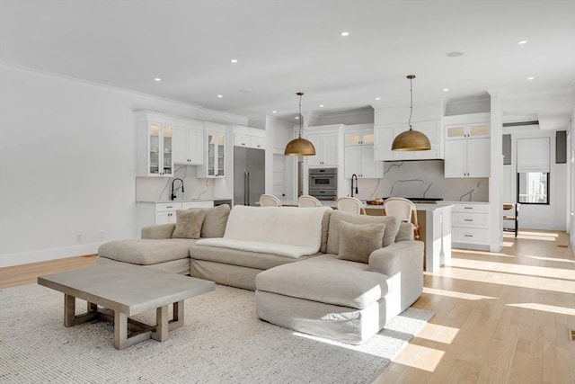 living area featuring ornamental molding, recessed lighting, light wood-style flooring, and baseboards