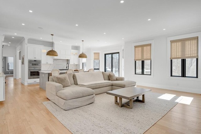 living area featuring recessed lighting, crown molding, and light wood-style flooring