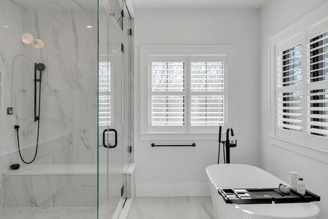 full bath with marble finish floor, a marble finish shower, baseboards, and a freestanding tub