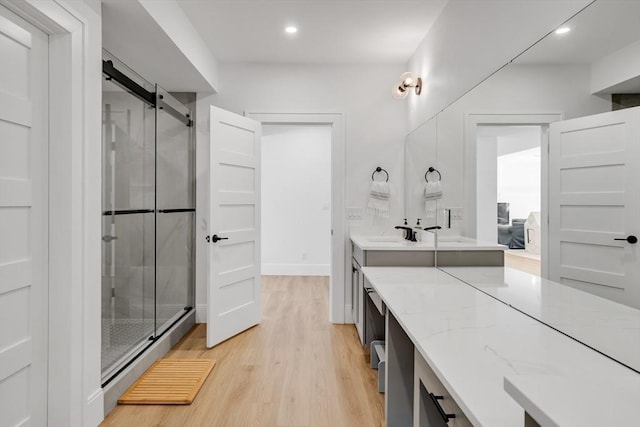 bathroom featuring recessed lighting, a shower stall, wood finished floors, and vanity