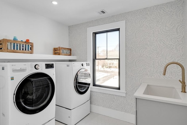 laundry area with laundry area, a sink, visible vents, washing machine and clothes dryer, and wallpapered walls