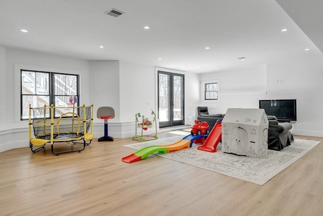 playroom with french doors, plenty of natural light, wood finished floors, and visible vents