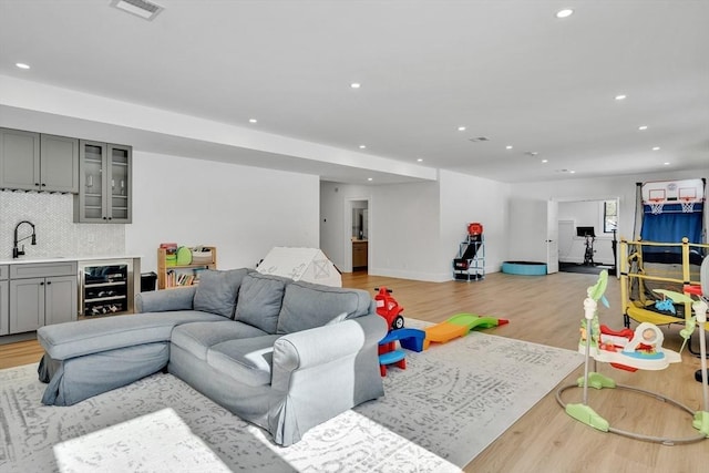 interior space featuring wine cooler, recessed lighting, visible vents, light wood-style flooring, and a sink