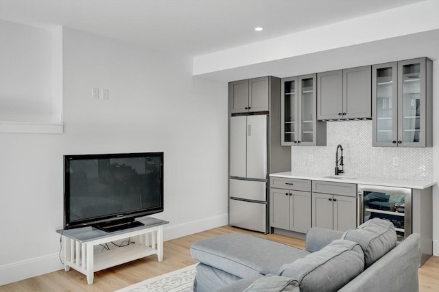 living area with recessed lighting, beverage cooler, baseboards, and light wood finished floors