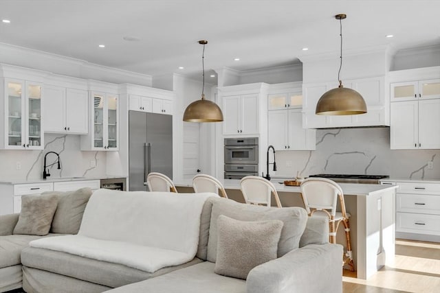 kitchen with light countertops, light wood-style flooring, appliances with stainless steel finishes, open floor plan, and a sink