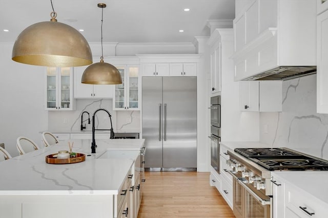 kitchen with premium appliances, white cabinets, custom range hood, and glass insert cabinets