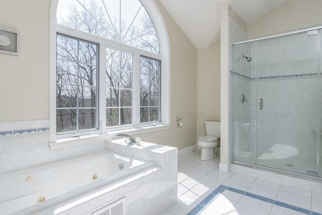 full bathroom featuring tile patterned flooring, vaulted ceiling, toilet, and a wealth of natural light