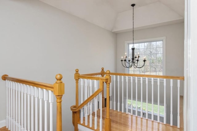 stairway with a notable chandelier, plenty of natural light, and wood finished floors