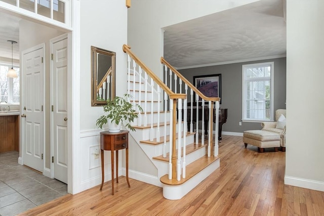 staircase with baseboards, wood finished floors, and a wealth of natural light