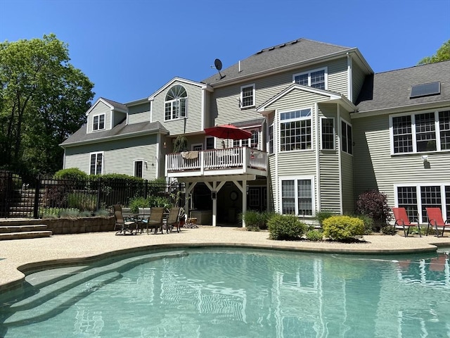 back of house featuring fence, an outdoor pool, a patio area, and a balcony
