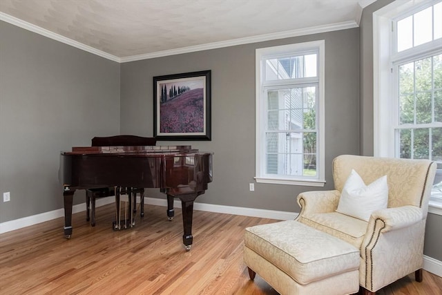 sitting room featuring baseboards, ornamental molding, and light wood-style flooring